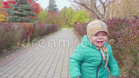 有趣的微笑一岁的男孩走在秋天公园的日落手里拿着面包快乐的童年概念慢慢视频的预览图