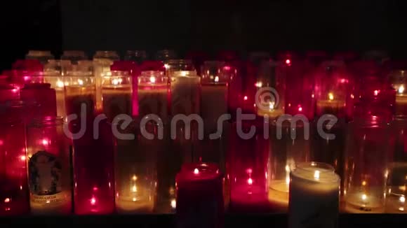 教堂里的小蜡烛在昏暗的教堂里燃烧着一排排蜡烛在黑暗的天主教教堂里点燃小蜡烛视频的预览图