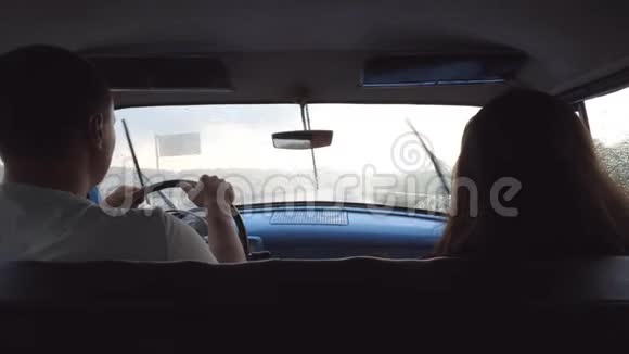 在雨天潮湿的天气里年轻夫妇骑着老式汽车不可辨认的男人和女人坐在视频的预览图