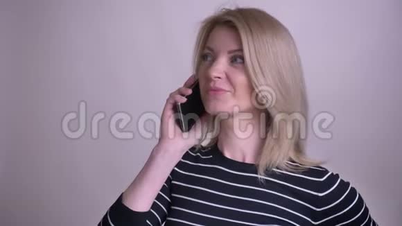 一位有魅力的白种人成年女性的特写照片她打了个电话微笑着背景被孤立视频的预览图