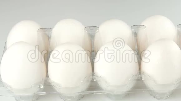 白色背景的透明塑料托盘中的大白鸡蛋女性的双手触摸每个卵子视频的预览图