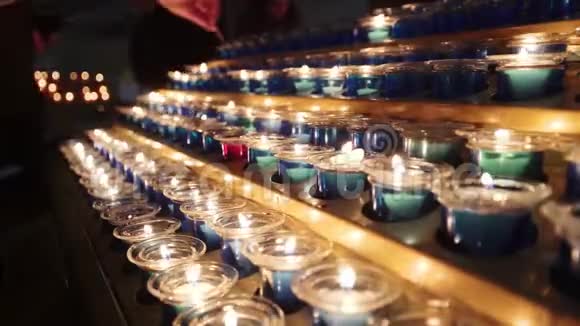 教堂里的小蜡烛在昏暗的教堂里燃烧着一排排蜡烛在黑暗的天主教教堂里点燃小蜡烛视频的预览图