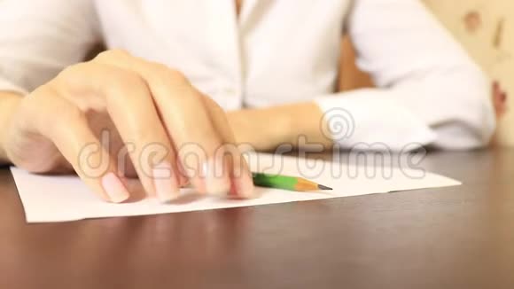 商务女性穿着白色衬衫坐在桌子旁拿着一张纸一支铅笔和敲击手指视频的预览图