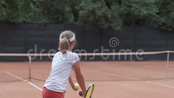 网球运动中的青少年女孩与对手在球拍上击球在球场上互相通过网视频的预览图