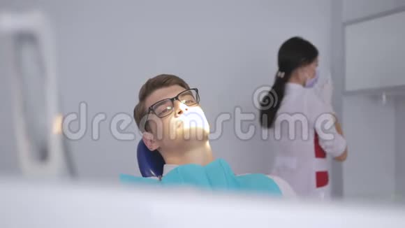 牙医打开灯把灯指向坐在牙科椅上的人视频的预览图