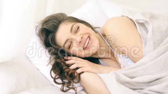 快乐微笑的女人在床上阳光明媚的早晨录像片段视频的预览图