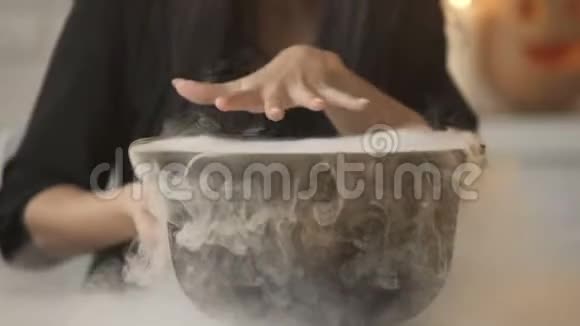 女巫变魔术用白烟把魔法咒语和烹饪药水放进锅里视频的预览图