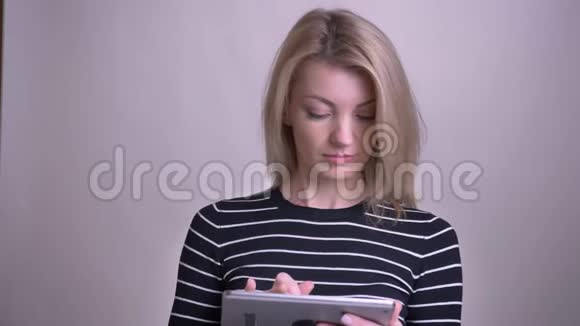 用平板电脑拍摄成年金发白种人女性的特写镜头并用绿色屏幕拍摄微笑视频的预览图