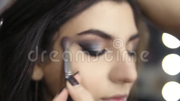 专业化妆师用特殊的画笔将眼影运用到模特眼睛上美容化妆和视频的预览图