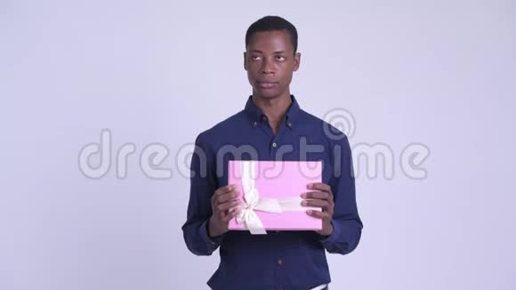 年轻的非洲商人拿着礼品盒思考视频的预览图