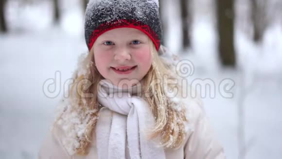 冬天森林里一个美丽的金发女孩的肖像下着雪视频的预览图