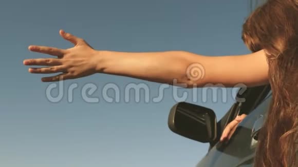 快乐的女性旅行者沿着乡间小路开车车窗上的手抓住了风长发女孩视频的预览图