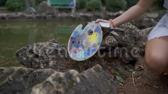 女孩艺术家为公园4k的风景画准备纸调色板和油漆刷视频的预览图
