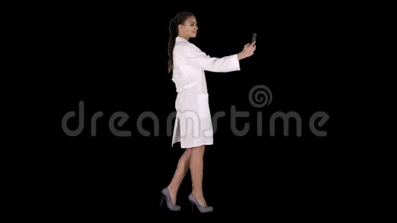 时尚的欧洲医生黑发女郎走路时在电话里自拍阿尔法频道视频的预览图