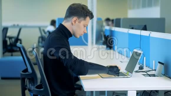 一个人造臂坐在键盘上打字的年轻人机器人机械臂概念视频的预览图