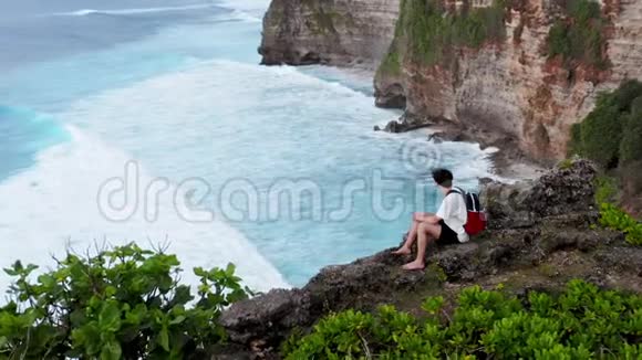 他坐在悬崖边上小男孩来到悬崖边坐下坐着看地平线的人男孩视频的预览图