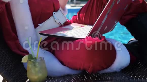圣诞老人在游泳池附近用笔记本电脑打字视频的预览图