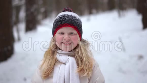 冬天森林里一个美丽的金发女孩的肖像下着雪视频的预览图