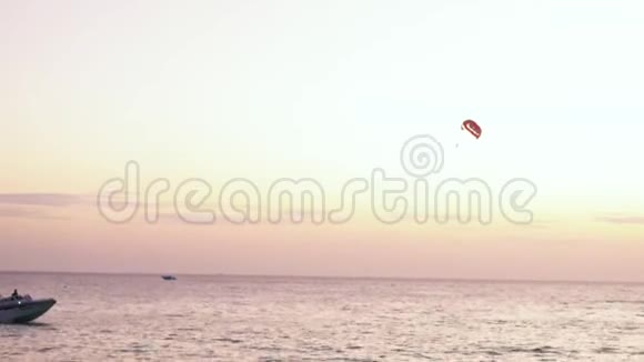 日落后在热带海滩进行降落伞活动与人一起拖着降落伞平静的海水视频的预览图
