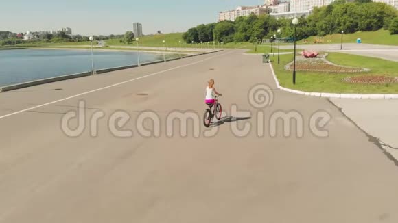 夏天在户外骑自行车的年轻女子河堤环保交通空中射击视频的预览图
