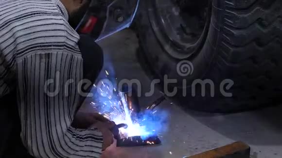 防护面罩中的焊工使用电焊连接金属部件红色的火花飞到两边视频的预览图