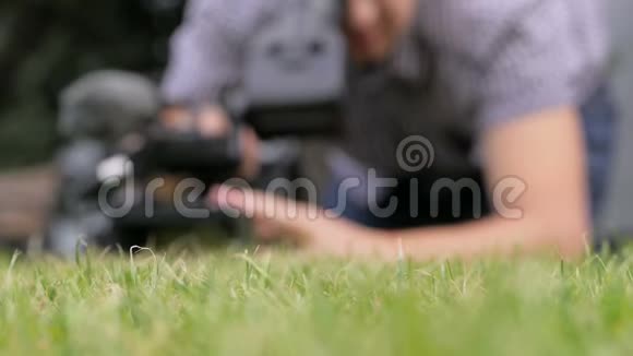 躺在草地上的摄影师正在拍摄视频的预览图