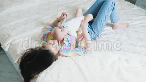小可爱的宝宝和漂亮的妈妈躺在床上视频的预览图