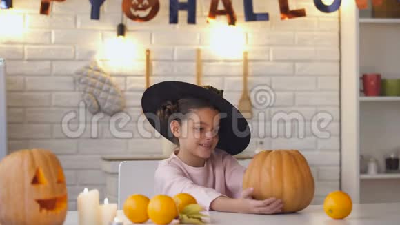 可爱的小女巫坐在万圣节派对上杰克南瓜竖起大拇指视频的预览图