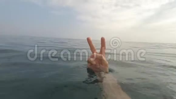 特写男子的手显示胜利v手势手势和标志设置蓝色海水的肢体语言视频的预览图