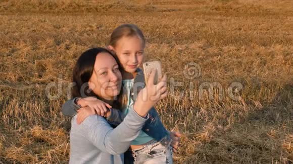 妈妈和女儿在麦田拍自拍照给手机视频的预览图