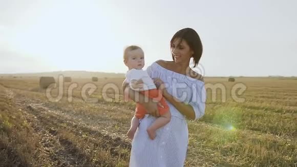 幸福的白种人母亲抱着她的小儿子的肖像她在日落时在田野里和婴儿玩耍快乐视频的预览图