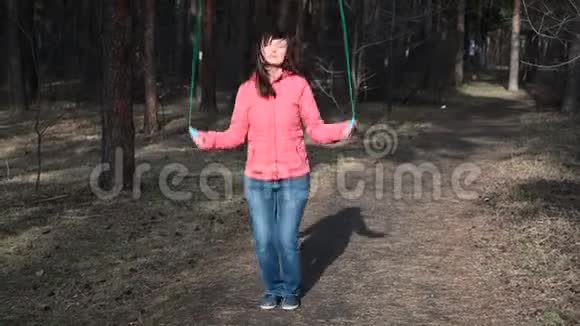 健身女子跳绳女生在秋树背景下阳光明媚的阳光下慢跑女生在户外训练视频的预览图