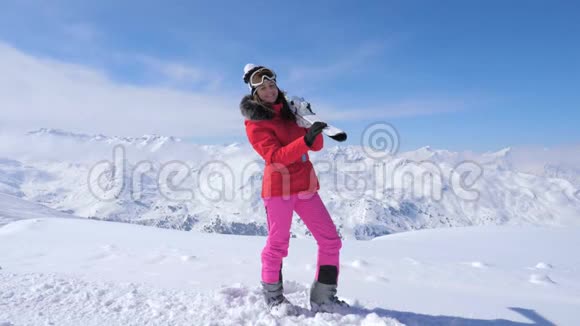 女人肩上扛着滑雪板站在背景山上视频的预览图