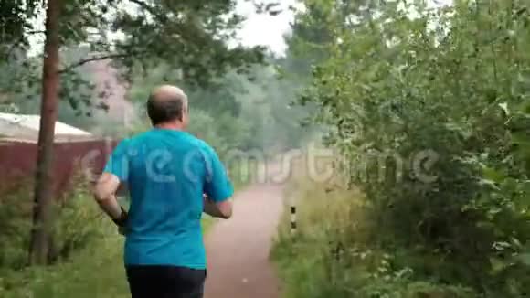 成熟的人在路上穿过树木后景视频的预览图