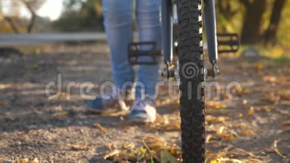 带踏板的自行车轮子特写女孩的腿在路上把自行车滚起来视频的预览图