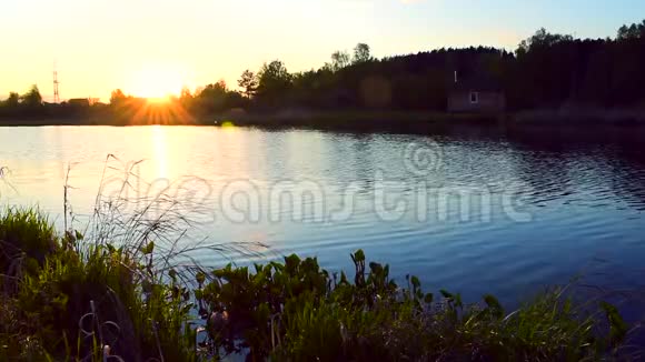 小湖的水在日落时慢慢移动岸边有一座小房子视频的预览图