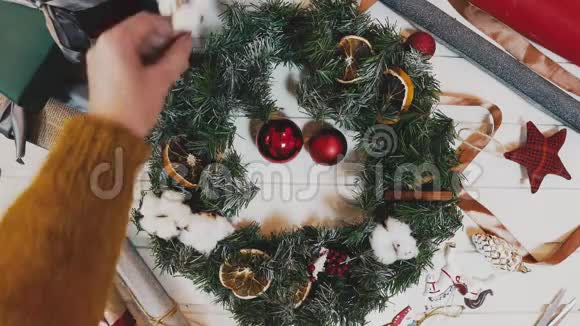制作圣诞花圈在灯光下美丽的女人手制作花圈视频的预览图
