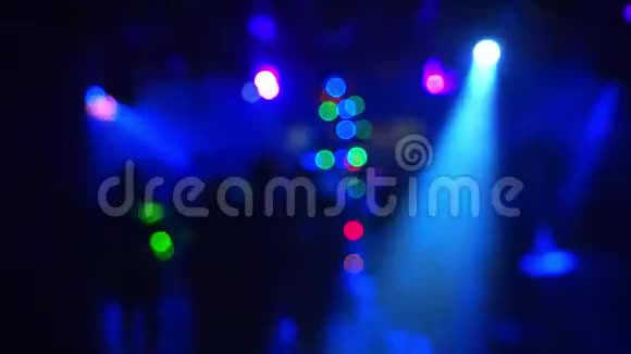 在聚光灯的彩色灯光下夜总会里跳舞的人模糊的轮廓视频的预览图