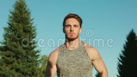 运动员在蓝天背景下在公园里跑步男跑运动员跑公园视频的预览图