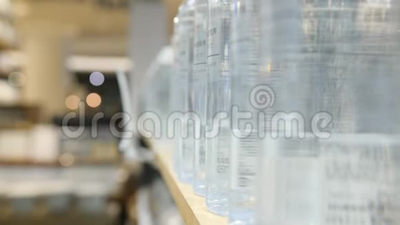 女性手拿补品水瓶从货架上的身体护理商店女购物者在商店里买化妆品4k慢速运动视频的预览图