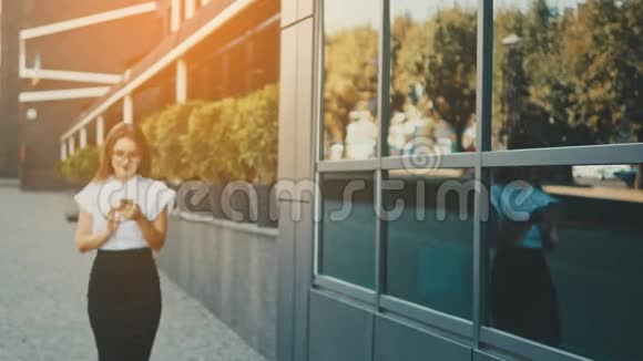 年轻漂亮聪明的商务女孩穿着商务服走路在这段时间里她把手机拿在手里视频的预览图
