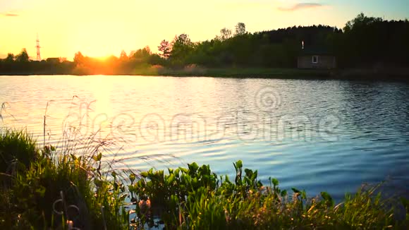 小湖的水在日落时慢慢移动岸边有一座小房子视频的预览图