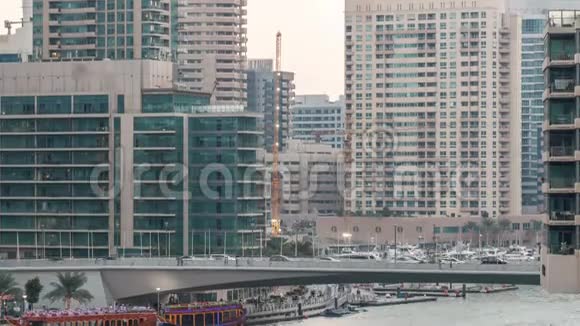 游艇和船只与游客停留在购物中心附近并通过桥下在迪拜码头地区的一天视频的预览图