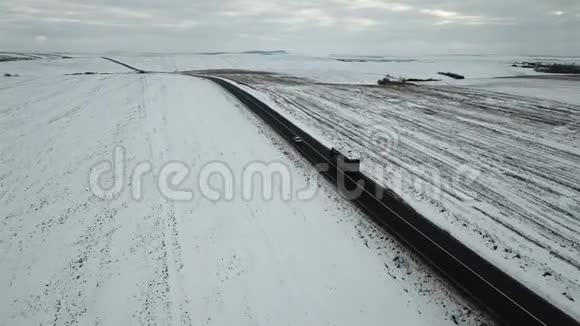 冬天的道路上积雪覆盖的田野鸟瞰景色视频的预览图
