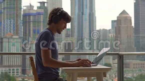 年轻的自由职业者在阳台上的笔记本电脑上工作背景是一个充满摩天大楼的市中心自由职业者视频的预览图