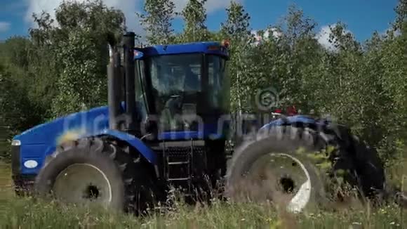 一个农民准备土地在桦树林附近用圆盘耙在拖拉机上播种视频的预览图