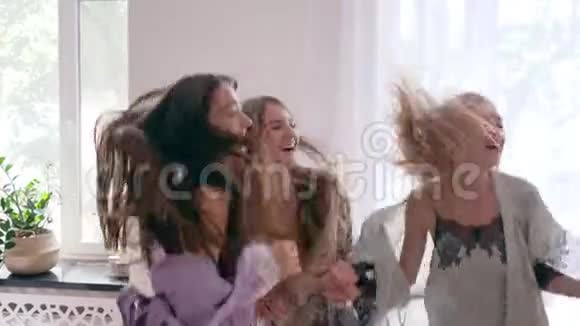 快乐的情绪快乐的年轻女人在床上跳跃在睡衣派对中慢动作视频的预览图