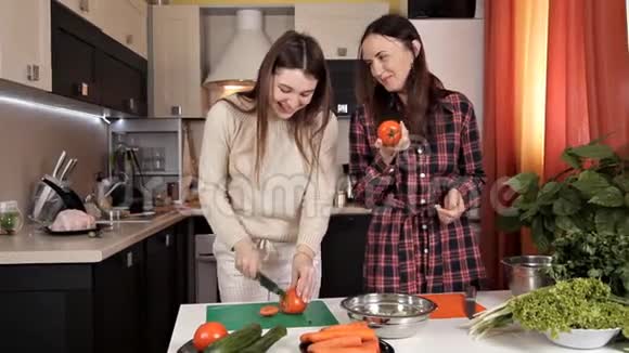 两个年轻漂亮的女孩在厨房准备一份蔬菜沙拉谈笑风生两个姐妹准备视频的预览图