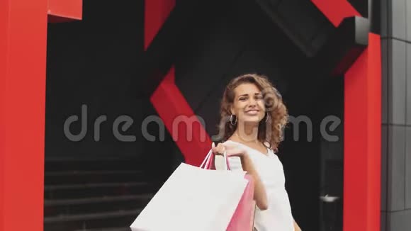 美丽的女人拿着购物袋微笑着购物中心背景视频的预览图