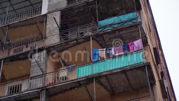 市贫困地区雨中挂在建筑物晾衣绳上的衣服视频的预览图
